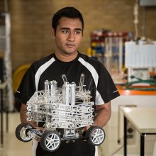Student holding robot created for the Warman Design and Build Competition